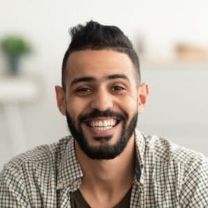 Smiling man with beard and checkered shirt in bright office.